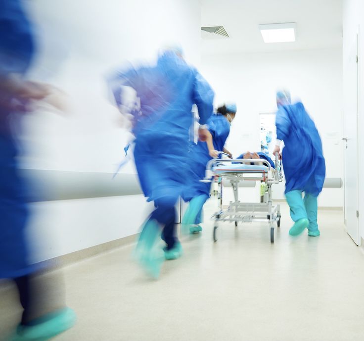 A care team moving a patient on a gurney down a hospital corridor